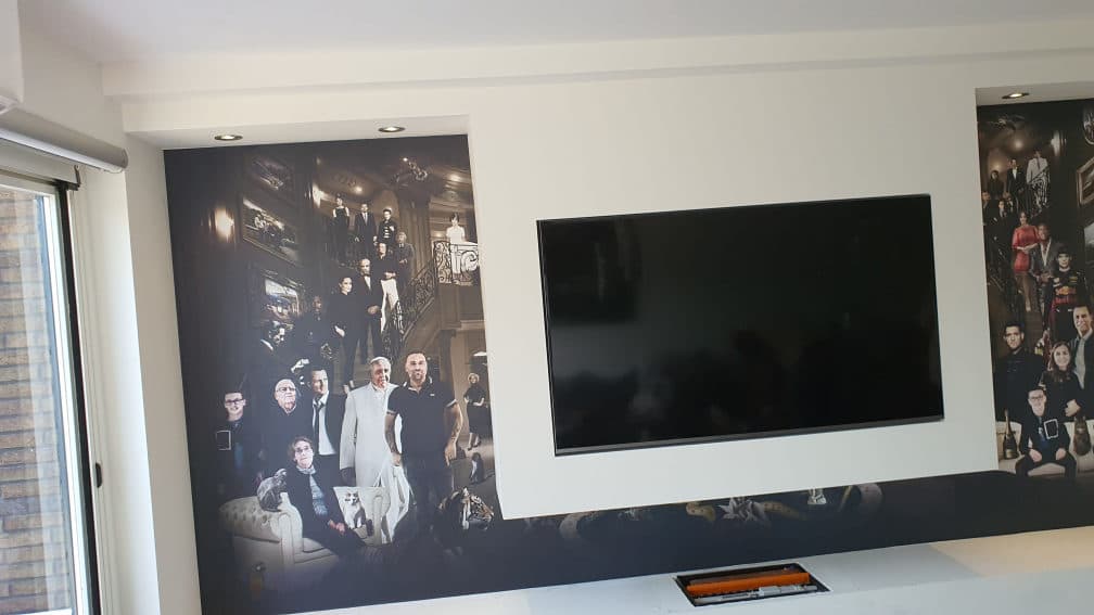 Handgeschilderde mural boven de mediawand in een grachtenpand-woonkamer