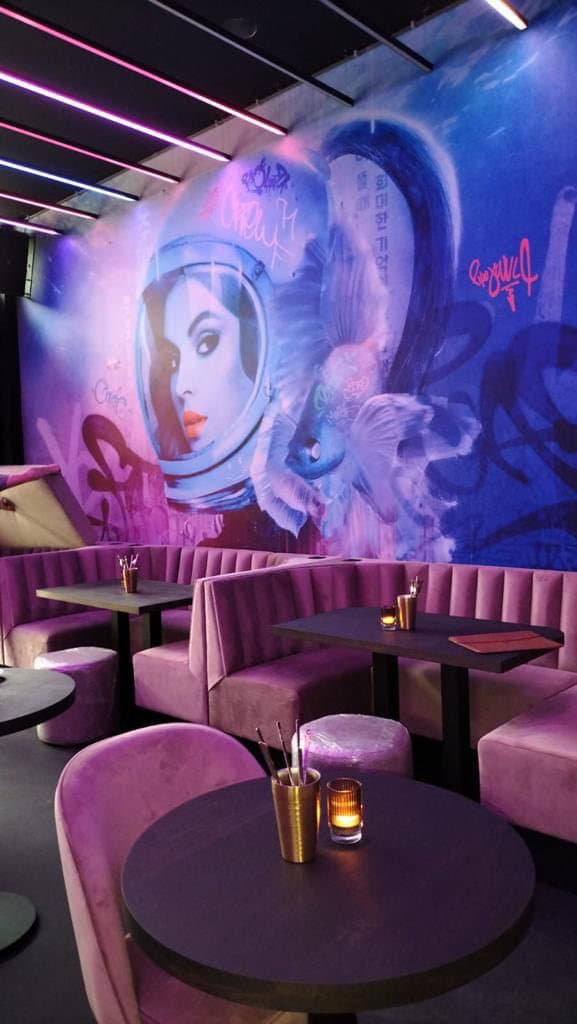 Neonverlichte lounge met een street-art portretmural